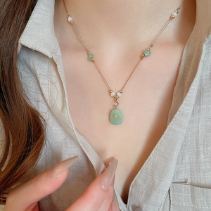 Détail d'un pendentif en pierre vert clair avec étoile croisée et chaîne perlée or rose