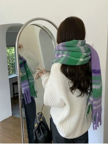 Close-up of a warm green and purple plaid scarf with stylish tassels for winter fashion