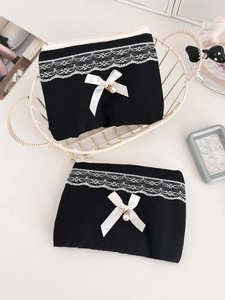 Detail of black pouch with white lace trim, ribbon bow and pearl pendant decoration