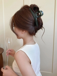 Detail of dark green hair claw clip styling a French twist on long brown hair