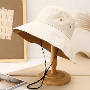 Beige wide-brim sun hat with adjustable windproof cord on a wooden stand