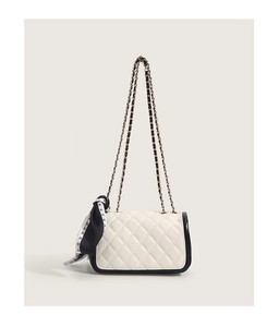 Détail du sac bandoulière matelassé blanc avec bordure noire et chaîne métal