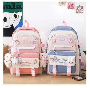 Close-up of pink and blue nylon school backpacks with cute badges and plush charms