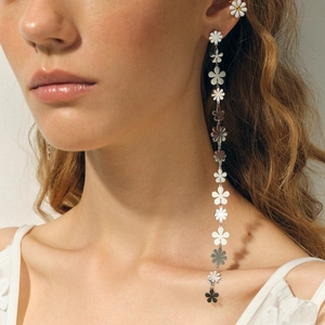 Détail de boucles d'oreilles pendantes marguerite en argent portées par un mannequin
