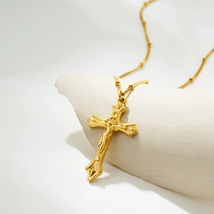 Close-up of golden crucifix pendant with Jesus relief on white textured stone display