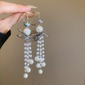 Macro detail of silver tassel earrings featuring pearls and sparkling crystals