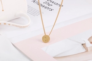 Detail shot of golden circular pendant with letter Q on a lifestyle magazine background