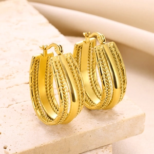 Close-up of gold geometric woven hoop earrings on natural stone background