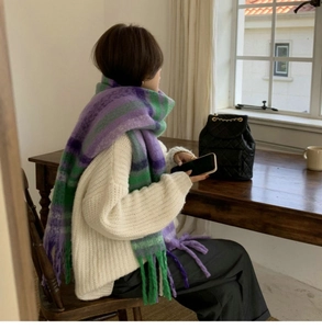 Detail of soft purple and green plaid scarf with fringe on a white sweater