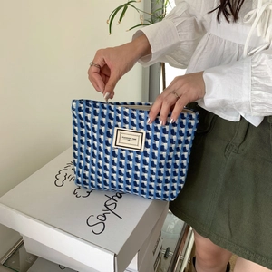 Gros plan d'une trousse de maquillage tissée bleue et blanche avec fermeture éclair
