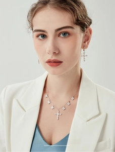 Detail of 925 sterling silver cross necklace and star earrings with white zircon on model