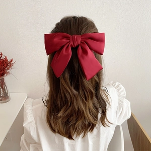 Detail of a large burgundy satin bow hair clip worn on the back of the head