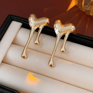 Detailed view of polished gold lava heart earrings with fluid metallic texture in a gift box