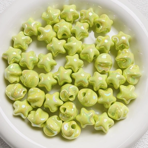 Macro view of light green iridescent star beads on a white plate for DIY jewelry making