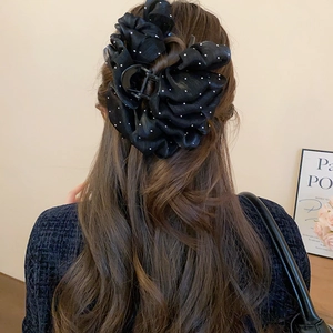 Detailed view of large black polka dot mesh flower hair claw clip worn by a model