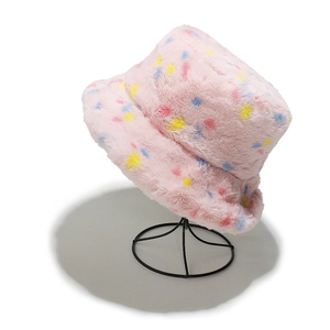 Detailed texture of pink plush bucket hat with vibrant colorful polka dots on stand