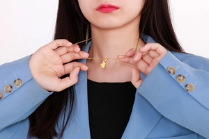 Collier avec pendentif violon doré tendance porté par un mannequin en tenue élégante