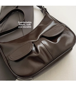 Detailed view of deep brown glossy leather hobo bag with unique pleated design and twin pockets