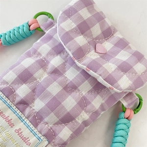 Detailed macro view of heart quilted pattern and woven strap on purple plaid camera bag