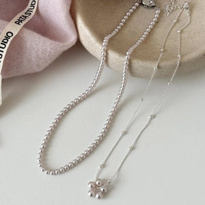 Ensemble de colliers de perles françaises avec pendentif fleur sur surface élégante