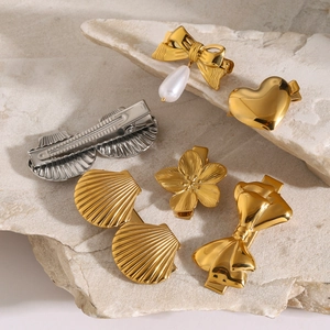 Close-up of assorted gold and silver stainless steel hair clips on natural stone