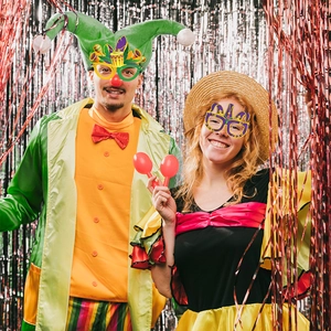 Coppia allegra che indossa occhiali di carta e maschere Mardi Gras con vari accessori