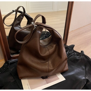Detail of dark brown PU leather hobo bag with silver hardware in a mirror reflection