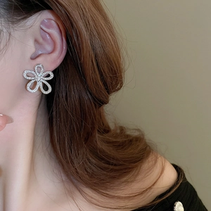 Close-up of sparkling flower stud earring with rhinestones on model's ear