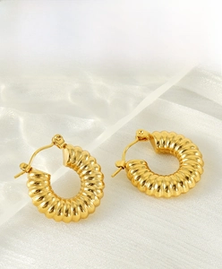 Close-up of 18K gold plated stainless steel hoop earrings with ripple texture on white silk