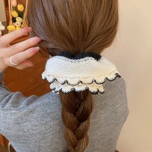 Close-up of black and white knitted lace scrunchie on a braided hairstyle