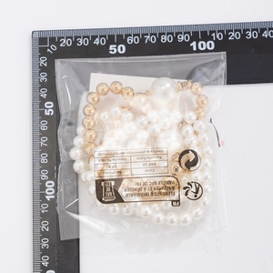 Detailed size measurement of a beaded pearl bracelet set beside a metric ruler