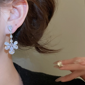 Close-up of a silver flower-shaped zircon earring worn by a model for elegant look