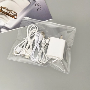 Close-up of portable transparent PVC bag containing a white charger and USB cables