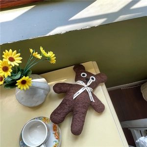 Cozy dark brown plush teddy bear with white ribbon on a desktop with sunflowers