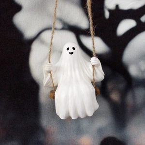 Close-up of ghost figurine sitting on a rope swing with detailed resin texture and black features