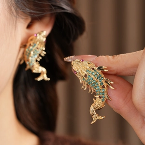 Detail view of vintage golden fish earrings with sparkling turquoise and pink rhinestones
