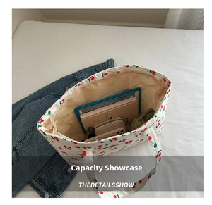 Internal view of a large white canvas tote bag with cherry prints holding books and tablets