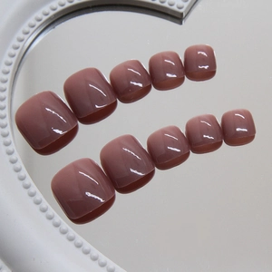 Glossy dust pink press-on toenails displayed on white mirror surface with reflection