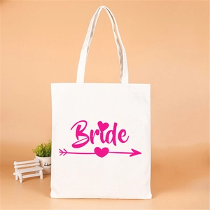 Close-up of white canvas tote bag with pink Bride typography and heart arrow detail