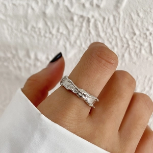 Close-up of a silver ring with irregular lava texture worn on a finger