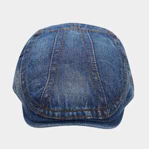 Detailed close-up of washed denim ivy cap featuring orange contrast stitching and thick fabric