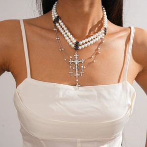 Detail of layered pearl sweater necklace featuring a sparkling rhinestone cross pendant