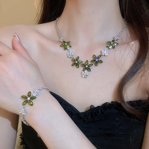 Gros plan d'un ensemble collier et bracelet fleur en zircon avec gemmes marquises vertes