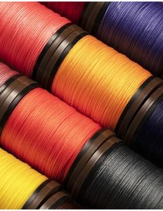 Close-up of vibrant 0.4mm round waxed threads on spools showing fiber texture