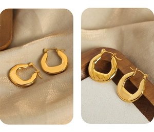 Close-up of gold-plated U-shaped earrings on elegant champagne silk and wood
