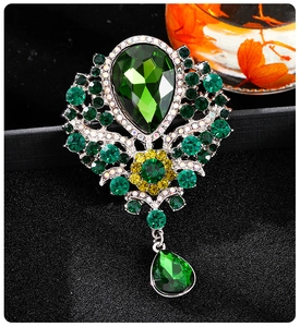 Macro detail of luxury brooch with pear-shaped green gemstone and sparkling crystals