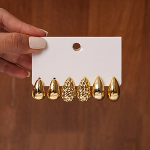Detail of three pairs of gold teardrop earrings with smooth and hammered metal textures