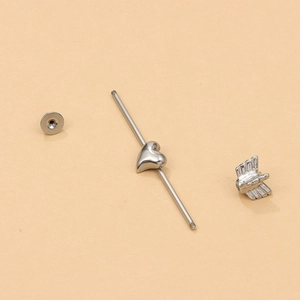 Polished silver heart industrial piercing bar showing modular screw parts and arrow end
