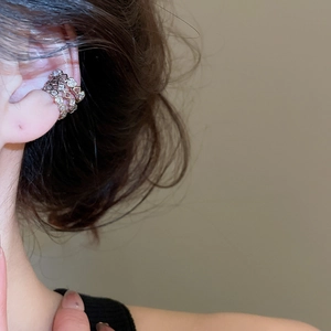 Macro detail of silver ear cuff featuring hollow heart shapes and sparkling zircon stones