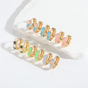 Close-up of colorful enamel star patterns on gold hoop earrings in diverse vibrant shades